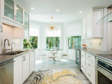 Fully stocked kitchen with dishwasher, stove, sink, bar fridge, and a breakfast nook with windows
